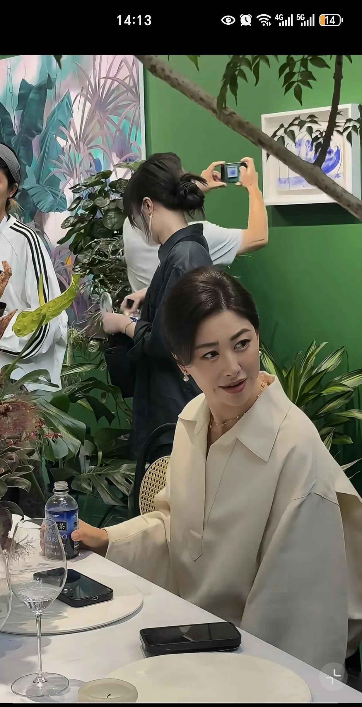 坐在桌子旁的她和三两友人闲聊，表情生动，姿态放松，没装嫩，也不显老，一举手一投足