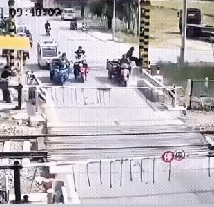 三轮车硬闯道口被杆子卡着了脖子，三轮车又开始后退，吓坏了道口值班人。紧接着，火车