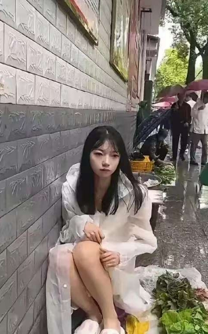 广东广州，有一位阿姨在回家的路上，看到有一名年轻的女子披着一件白色的雨衣，坐在摊