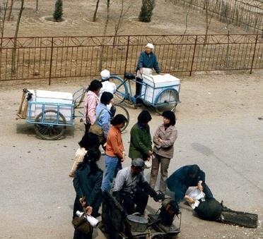 这是1983年沈阳街头摊主炸爆米花。爆米花摊位围满了人。她们都是排队等着炸自己的