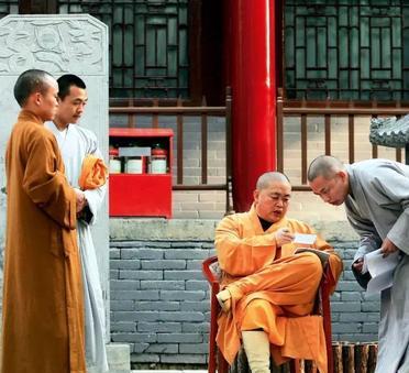 2005年，少林寺的一名僧人向方丈释永信汇报工作。释永信坐在圈椅上，翘着腿，认真