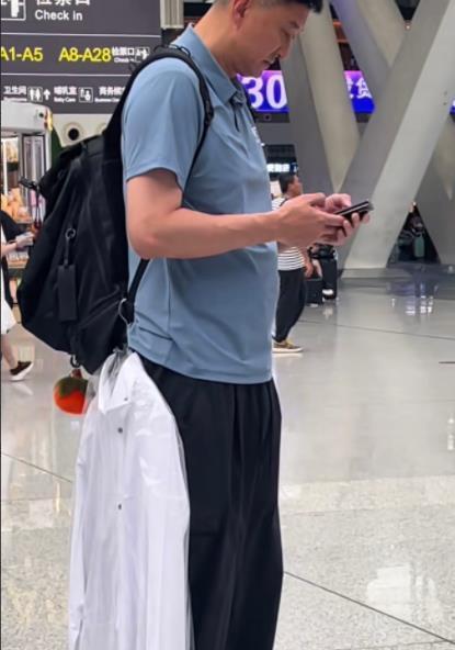 谁知道广东队主教练杜锋这是什么造型啊？在飞机场准备登机时，身上却挂了一件白衬衫，