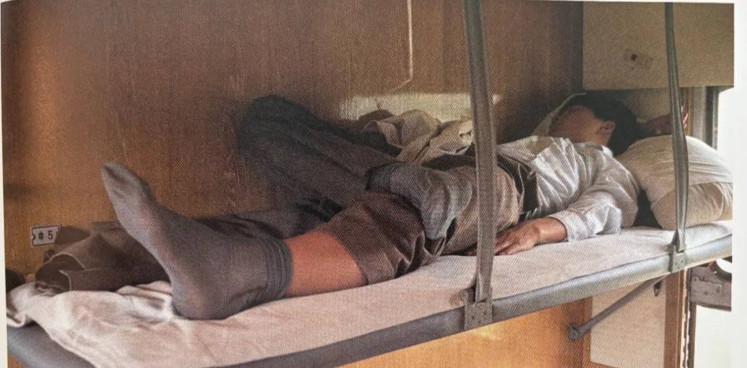 80年代列车硬卧中铺，一男士穿着凉鞋配丝袜打盹。