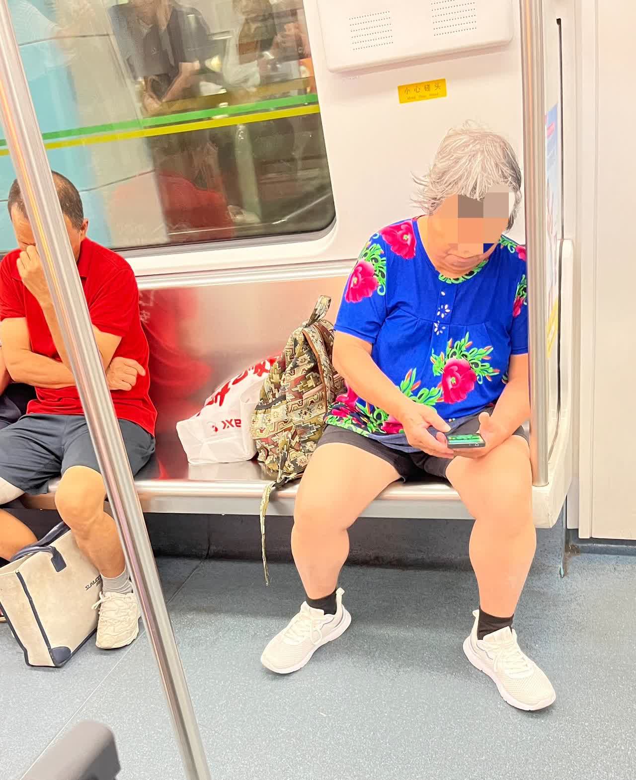 这位穿着花衣裳头发发白的大妈大张双腿坐一个位，她的两件行李放一个位，然后旁若无人