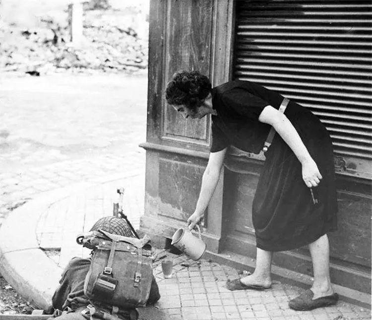 1944年夏天，诺曼底战役期间，一位法国妇女为一名英国士兵倒茶。这一幕发生在战火