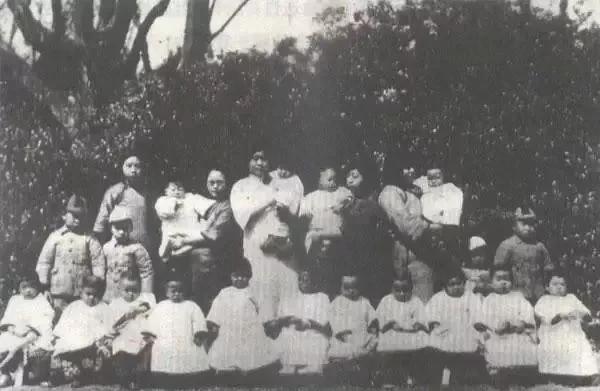 1930年，上海大同幼稚园的老师和孩子们留下了一张合影照片。
照片中排：左一为毛