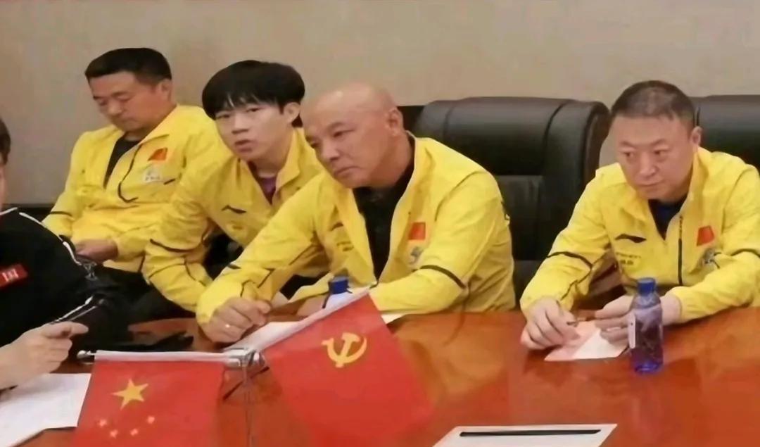 这应该是昨天在公园参加活动之后开会的场景。
运动员和教练员都穿着厚厚的长袖队服，