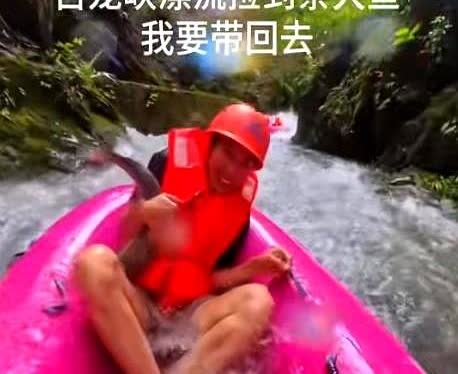 广东一男子在玩漂流时，怀里突然多了一个东西。

当他反应过来时，立即死死抱住