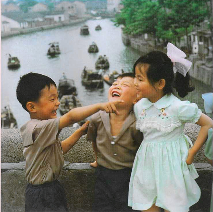 1980s，三个小朋友在苏州古运河石桥上玩闹，他们的穿着相比农村小孩洋气了许多。