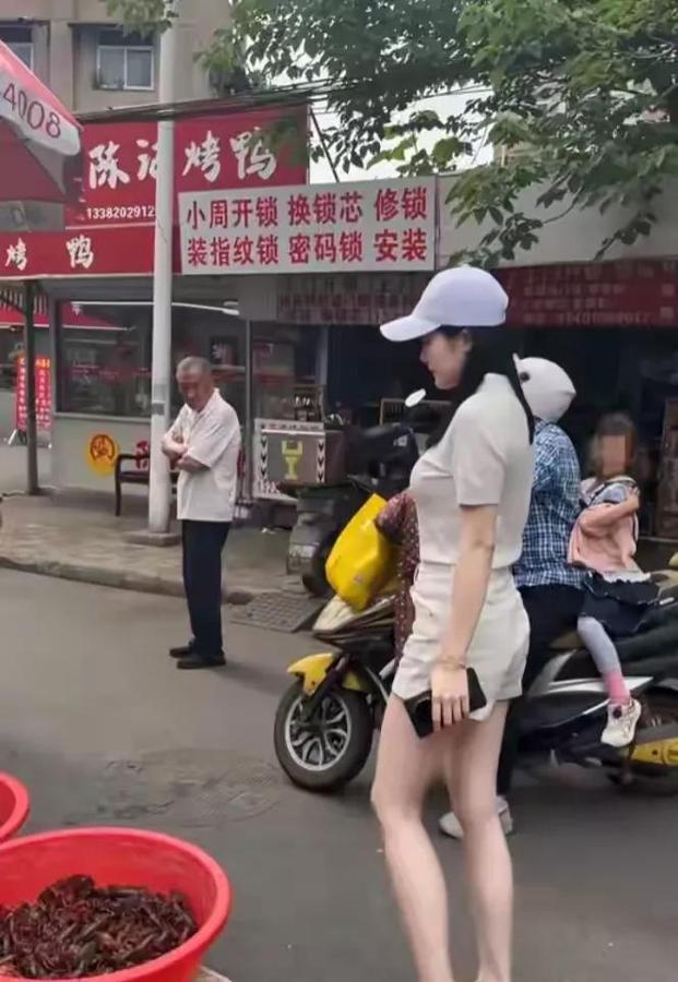 这才是南京城最靓的风景线！清晨的菜市场里，一位高挑时尚的姑娘提着五六斤小龙虾快步