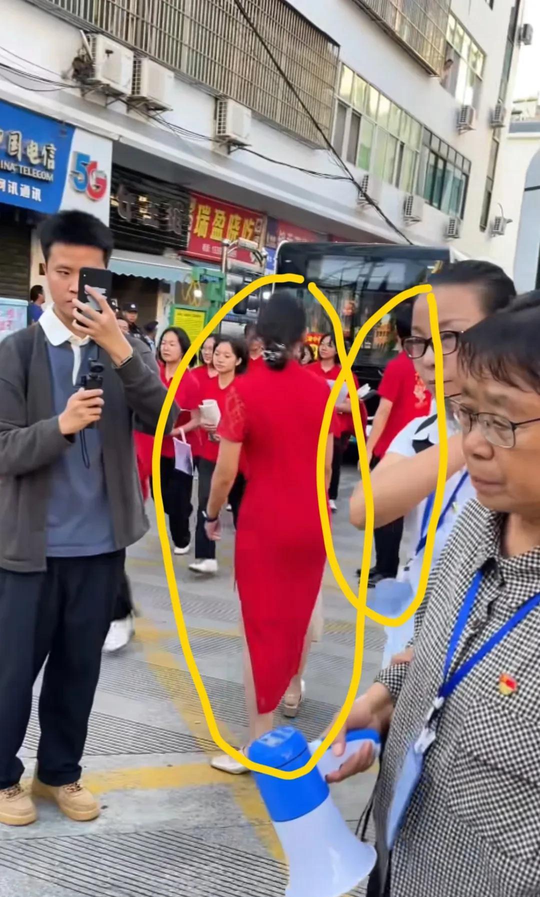 张桂梅送考，大巴车旁有两个人，一男一女在管理，这个不知道是不是华坪女高老师。
女