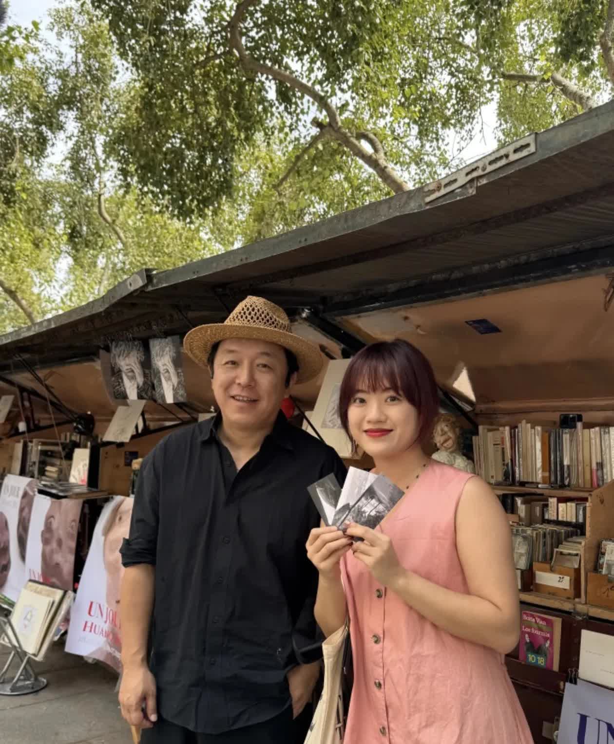 50岁的黄渤在法国巴黎摆摊，他比之前圆润了些，穿着一身黑色休闲服戴着一个编织帽，