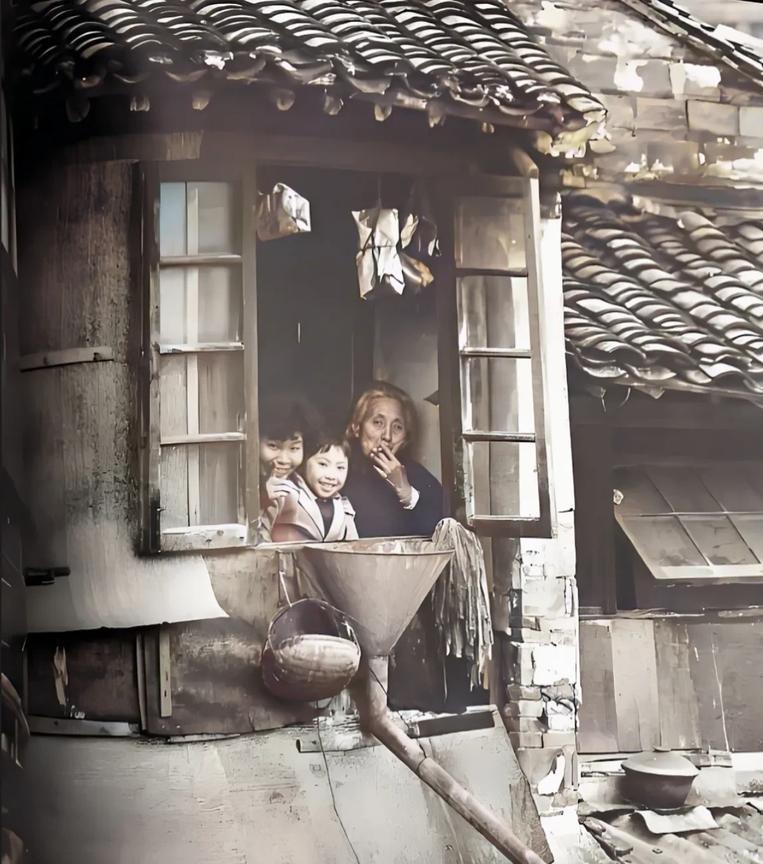 80年代，苏州。一位老奶奶、妇女和一个小女孩，坐在具有瓦屋顶和砖墙的二楼窗台上，