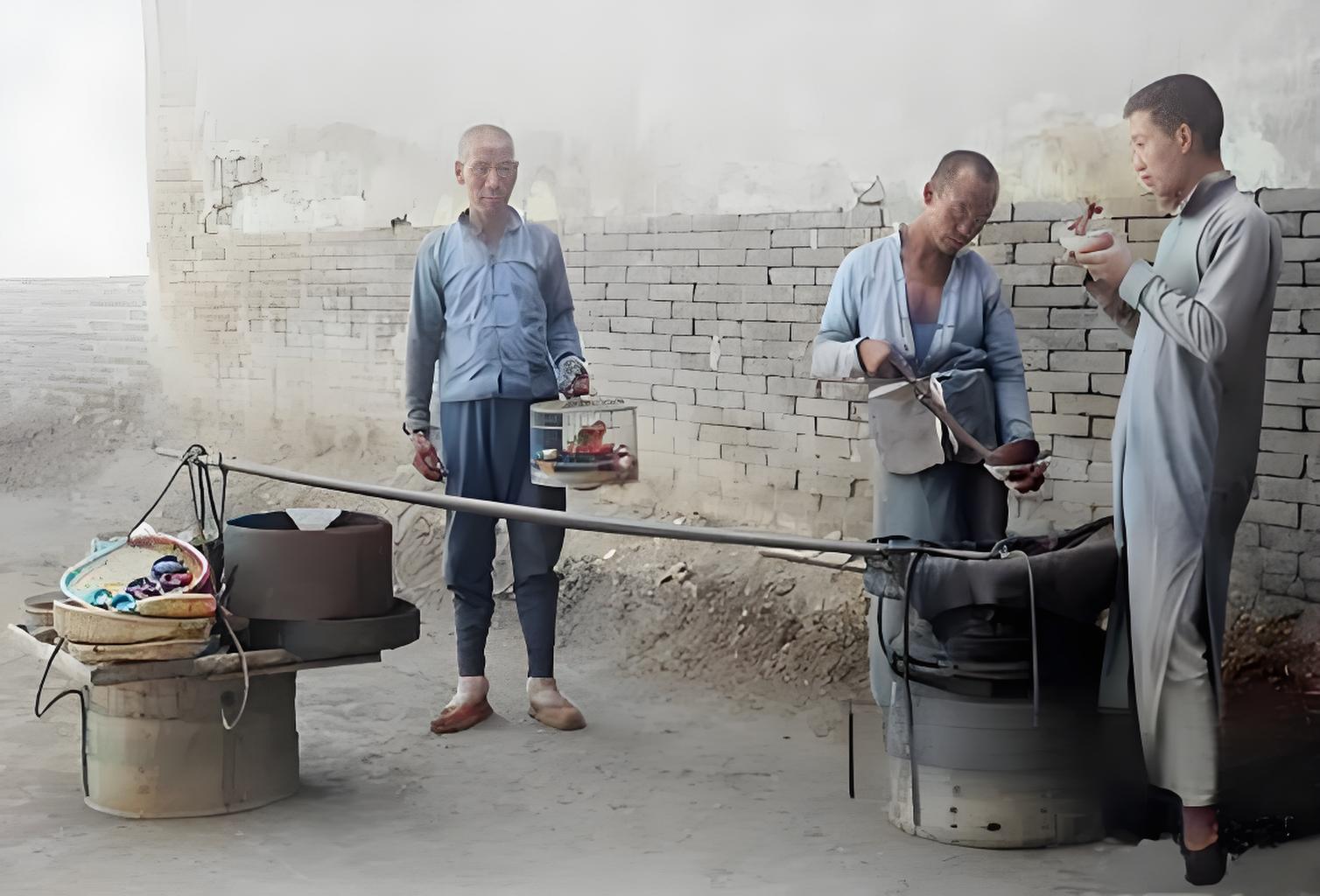 这是民国时期街头小商贩的场景。三位男子在砖墙边，中间男子挑着担子，两侧有炊具、容
