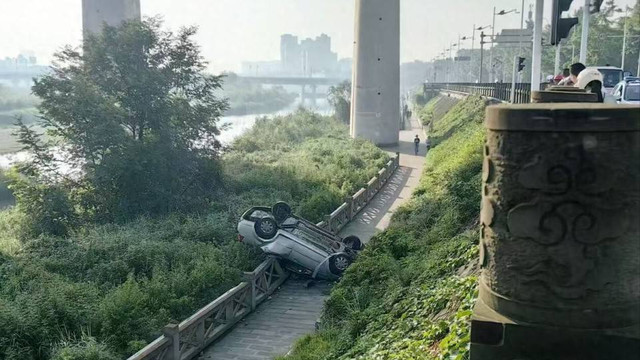 轿车撞破护栏倒扣在河堤旁，驾驶员自行脱困，四川广汉警方正调查