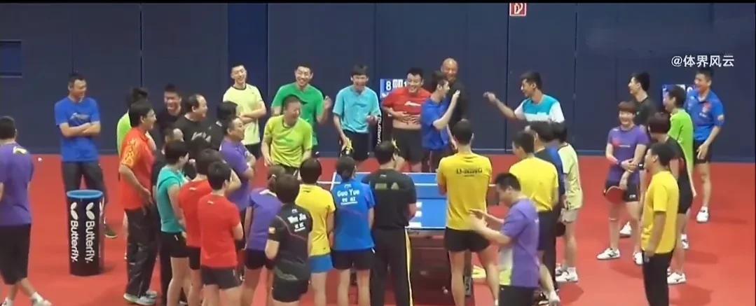 这是十年前刘国梁带领队员观看张继科演示发球的画面。
图中的教练和队员其乐融融，画