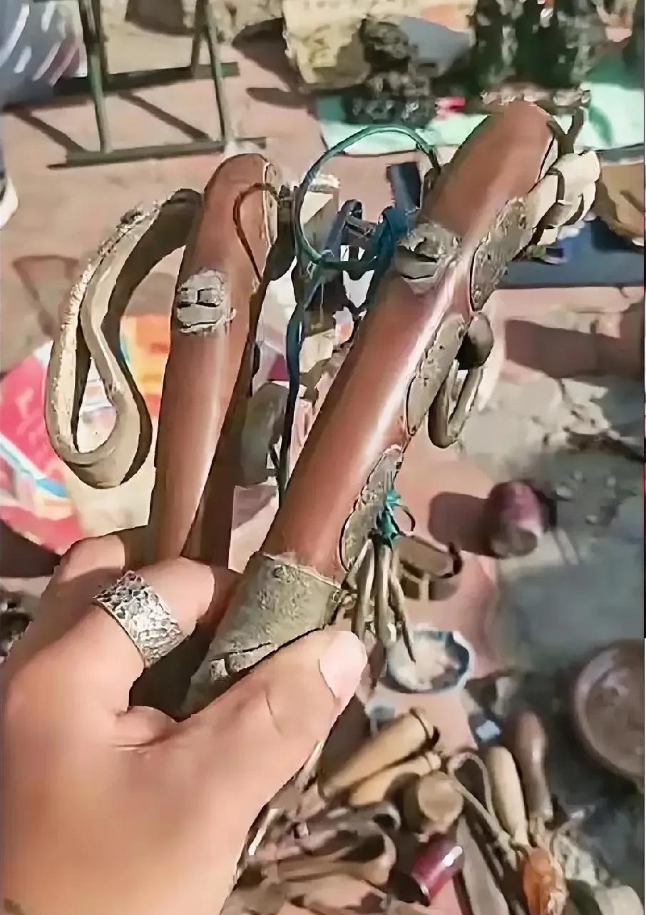 在旧物摊上，一只手握着这两件古朴物件。瞧它们带着岁月痕迹，皮革与金属的搭配透着神