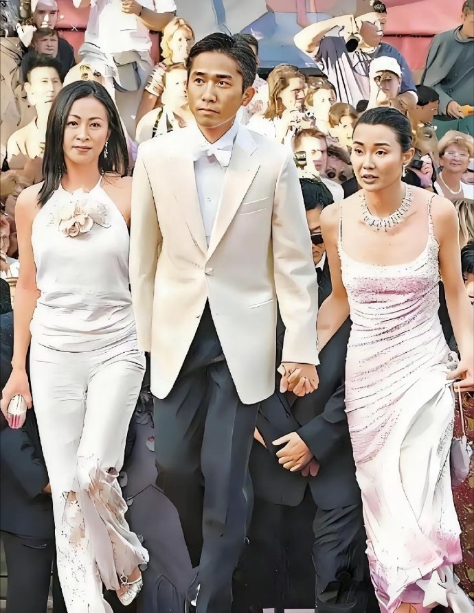 这张照片拍摄的是2000年戛纳电影节红毯上的经典一幕
梁朝伟一手牵着女友刘嘉玲，