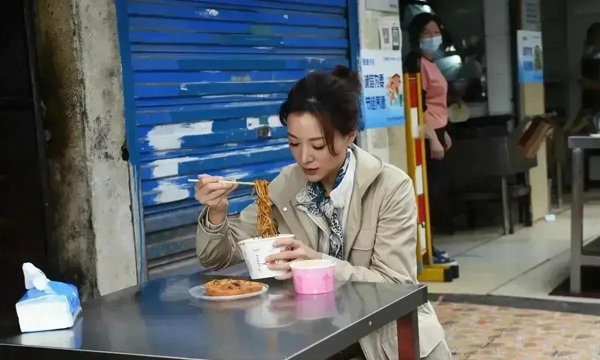 董卿的气质真是无敌了，在路边摊吃面都如此优雅，画面中的董卿穿着朴素，正在路边吃小