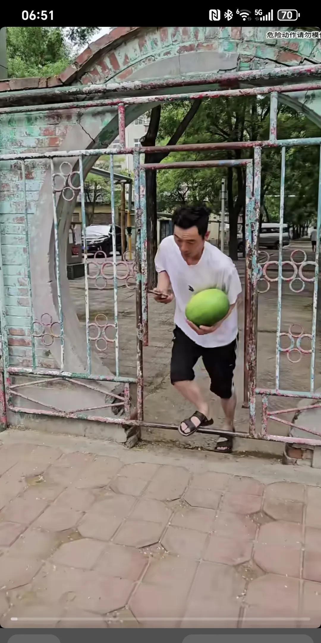 缘份让我们在此相遇～
白衣男子捧着一个西瓜，边走边看手机，出小区门时不小心被门槛