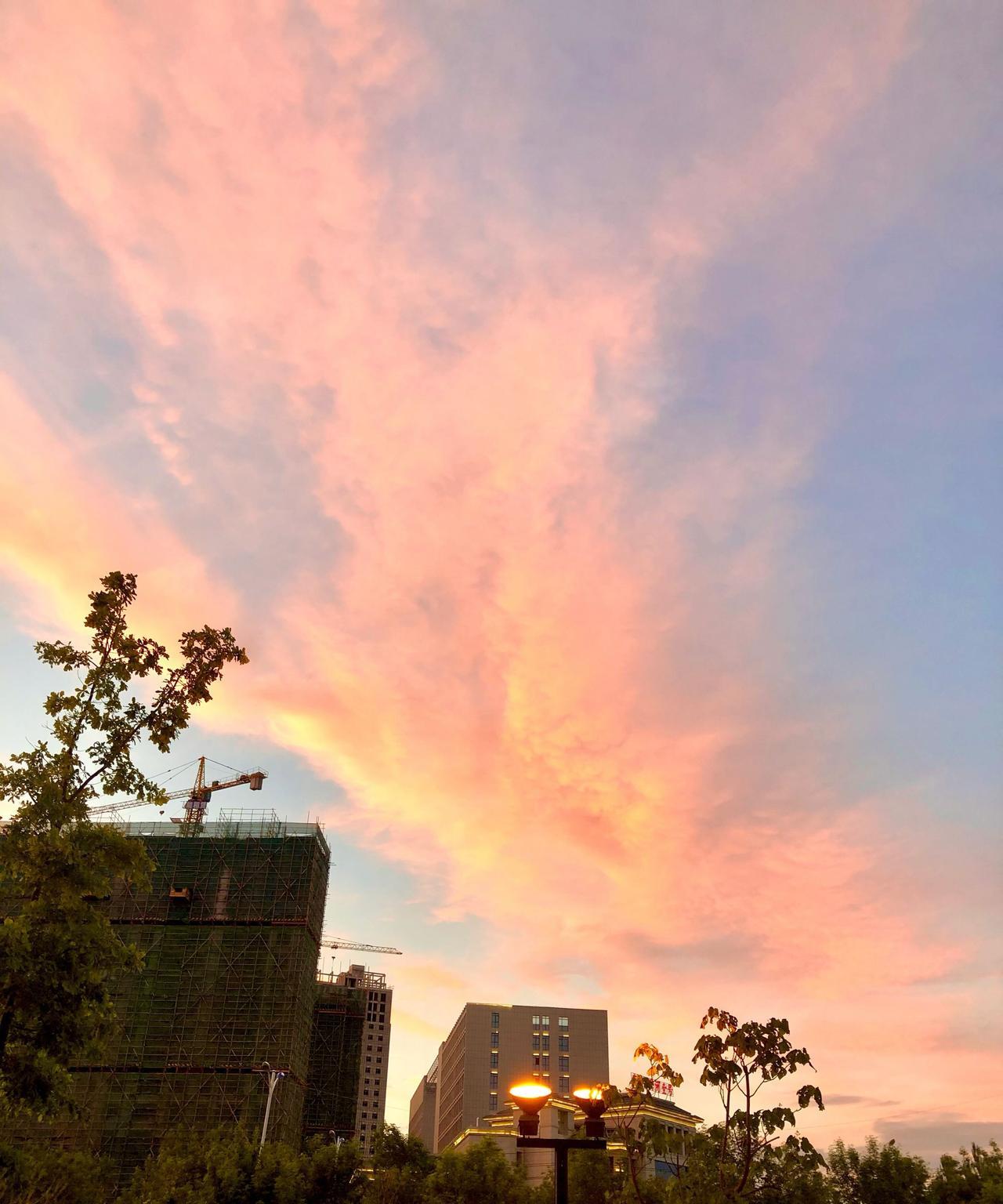 夏日里的晚霞如梦如幻，橘红、排紫与金黄交织成如揉碎的彩虹，将天空染尘流动的油画。