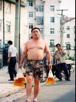 1992年夏天的一个傍晚，青岛，一个男士光着膀子手拎三袋啤酒，这是回家喝酒去了。