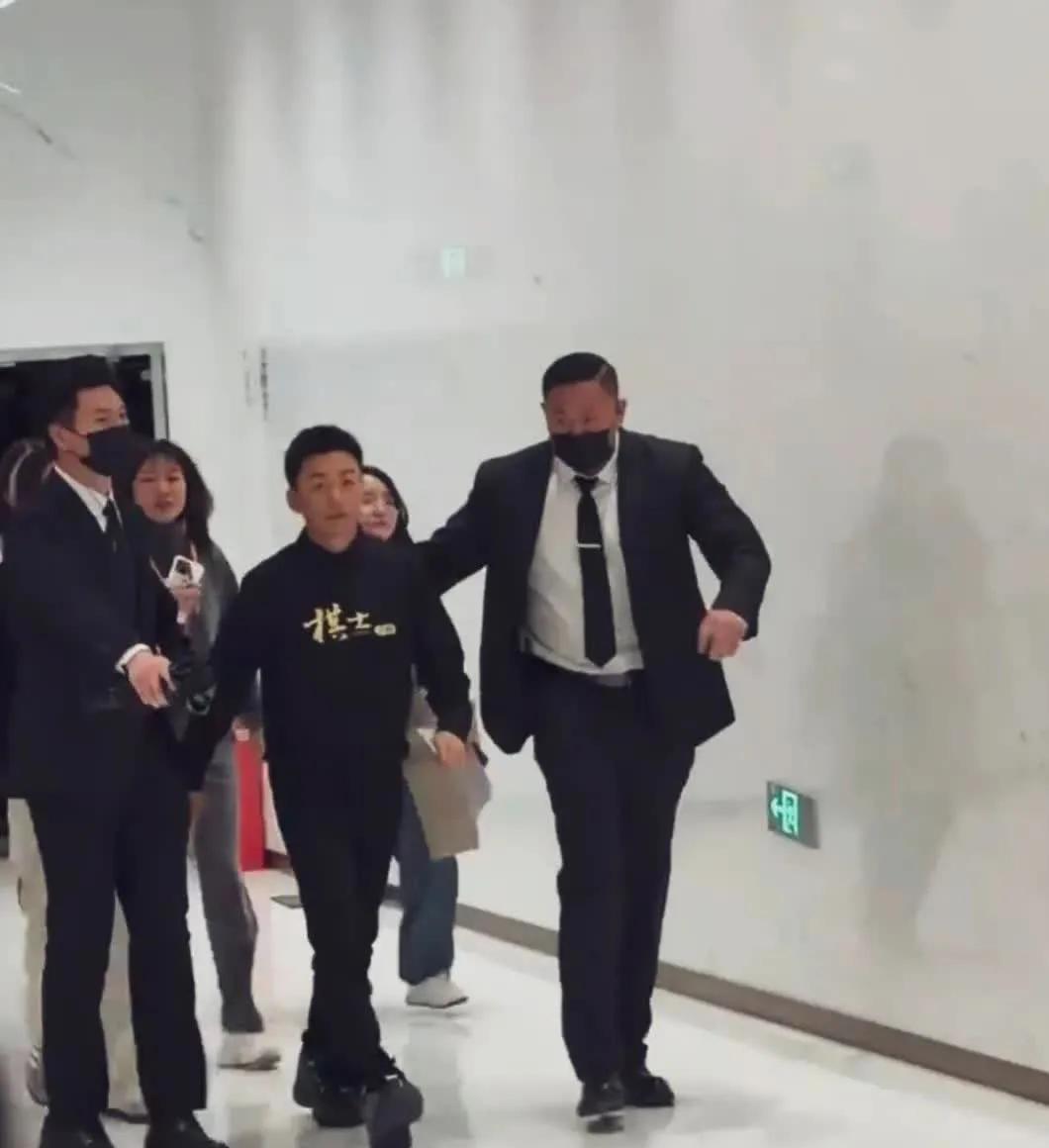 王宝强个子不高，一身黑衣，有两个高大帅气的安保人员亲自互送下快速走来，走路特别有