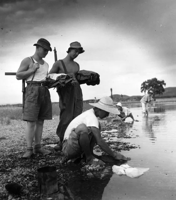 1950 年 9 月 16 日，朝鲜战争期间，两名英国士兵将脏衣服交给一名韩国洗
