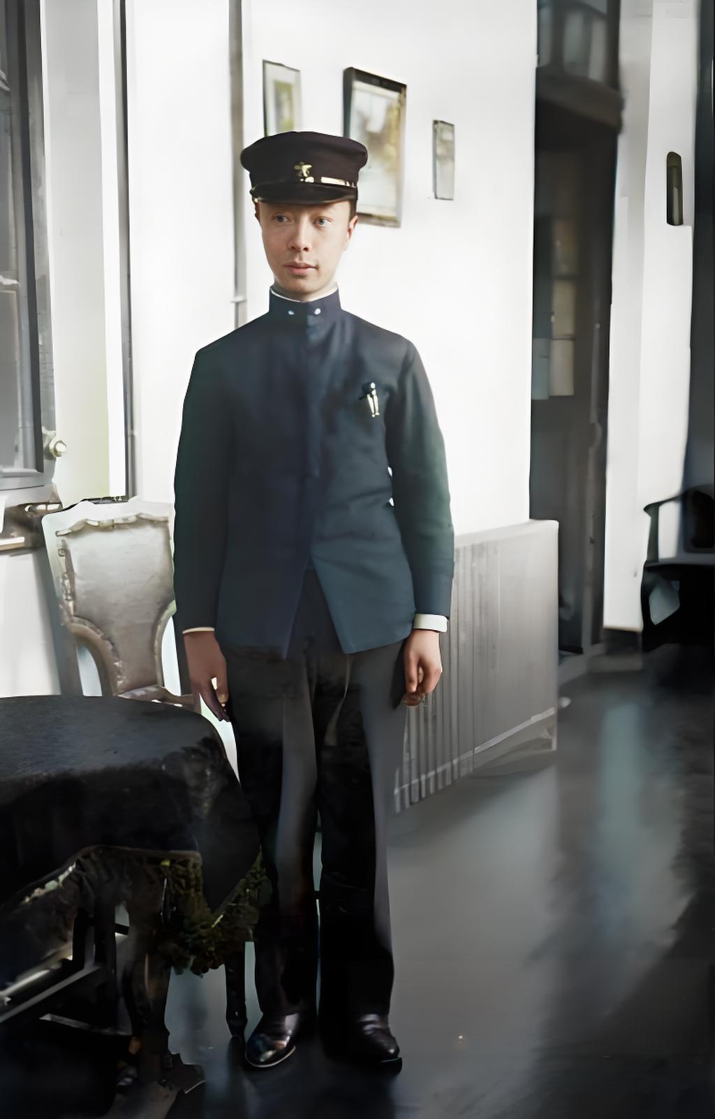 20世纪初的室内，溥杰身着日式学生制服，戴制式帽子，笔挺站立。背景是简洁的墙面与