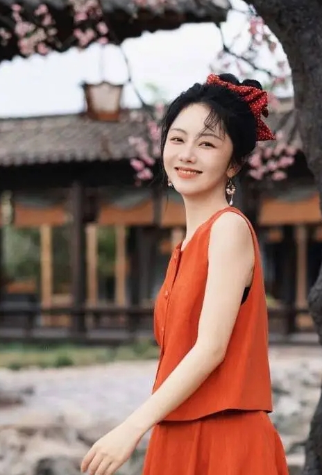 谭松韵穿着红色连衣裙，手拿西瓜，表情娇俏可爱。