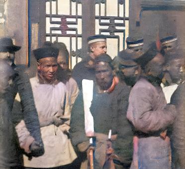 1900年12月31日，两名正要行刑的刽子手抱着大刀站在人群前。这把行刑的大刀与