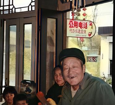 这是1995年山东省滕州市的农村里通了公用电话。一位老农拿起话筒高兴得合不拢嘴。