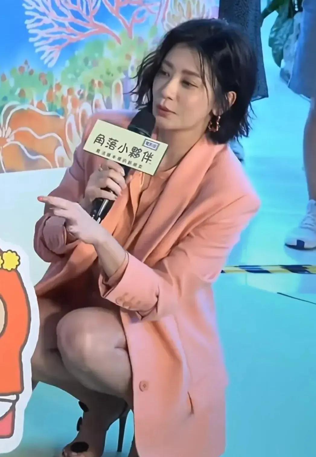 镜头中的贾靖雯身材正点，眉眼如画，琼鼻秀挺，红唇若玉，衣着精致，蹲姿优雅，可是人