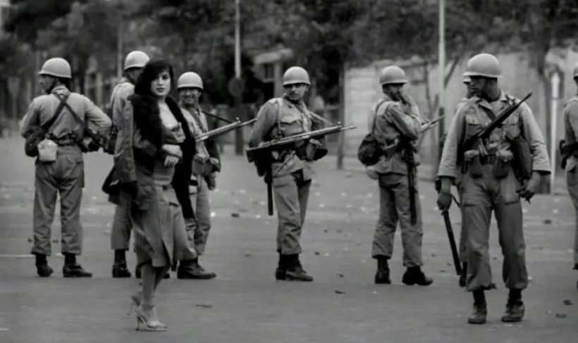 这是1978年的某一天，革命前夜的伊朗街头，士兵们在维持秩序。这位女士可能是一位