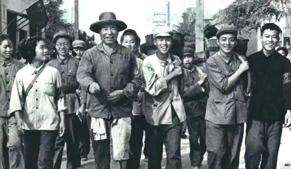 1966年，北京的学生们与全国劳模时传祥在一起，兴高采烈，笑容满面，一起掏粪背粪