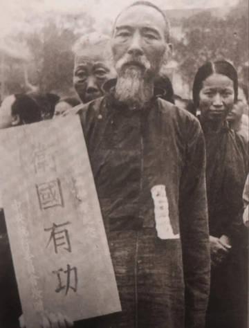 抗战时期，在四川省，成都市，一位牺牲战士的父亲领取“卫国有功”的牌匾。

老者失