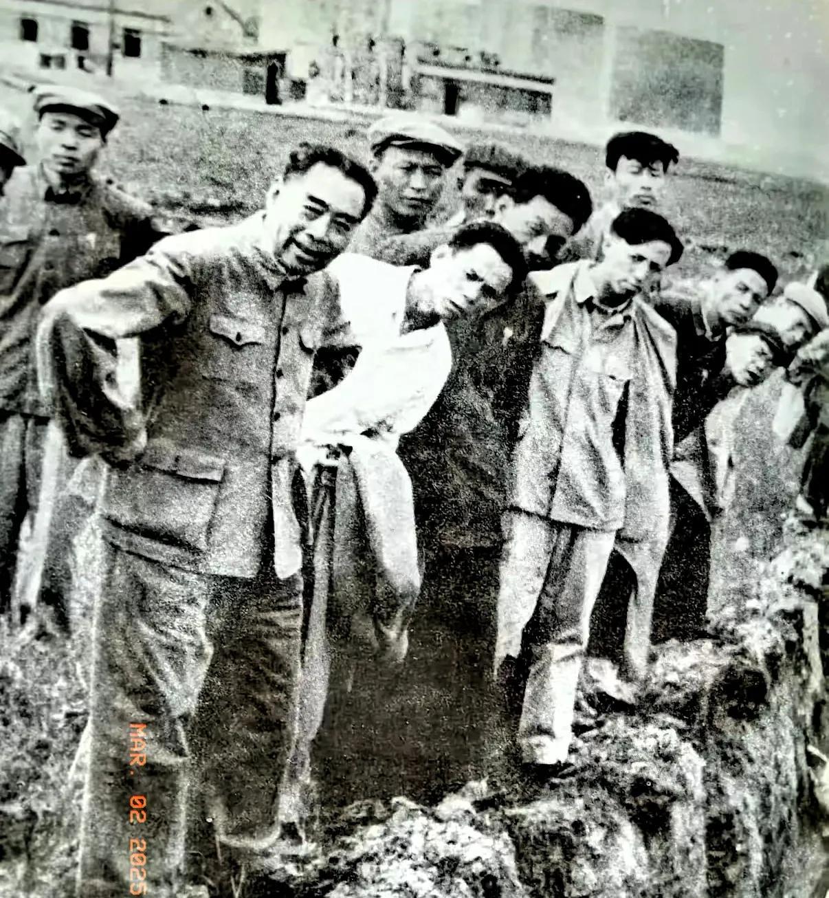 一张珍贵的黑白老照片。
画面中的场景，仿佛又回到了那个年代，周总理踩着泥泞的土地