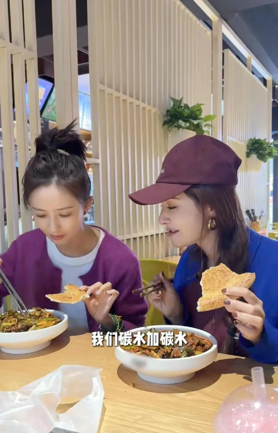 佟丽娅和麦迪娜在一起吃新疆炒米粉，手里都还拿着馕，大口大口吃。而娜扎吃新疆炒米粉