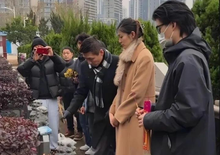 张子健和女儿来墓园给已经去世的前妻李婷扫墓时的一幕，只见他躬身排放祭品对前妻的情