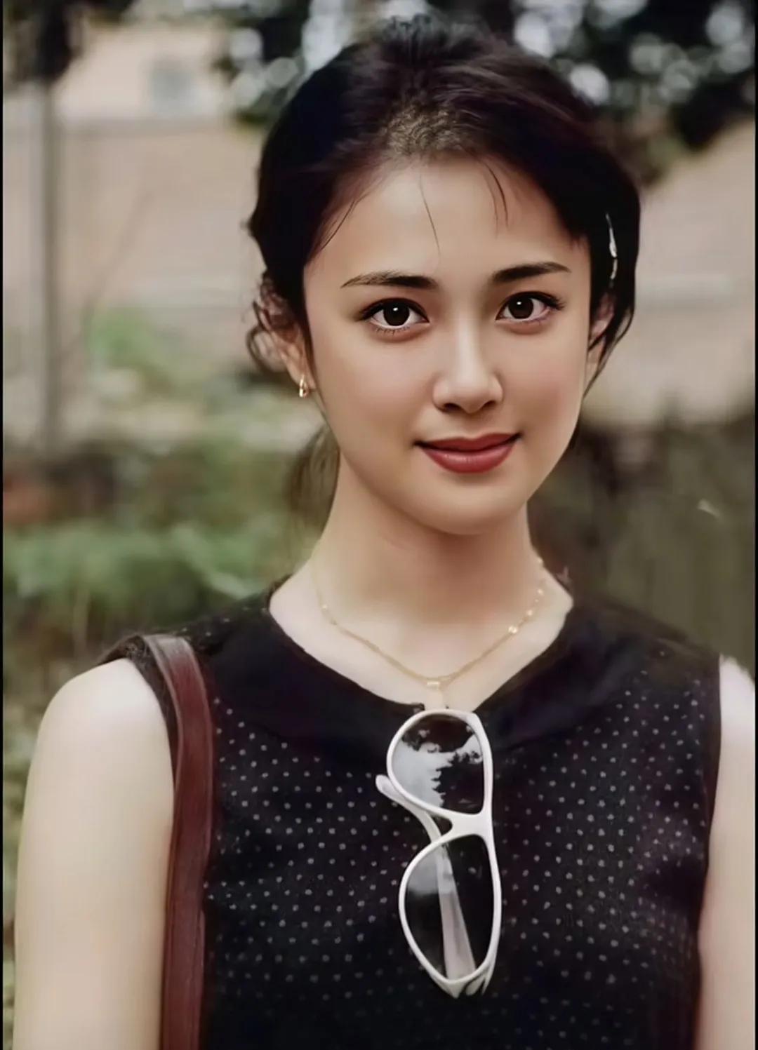 她静静地站在那里，似一幅灵动的画。乌黑的发丝随意挽起，几缕碎发俏皮散落。简约的黑