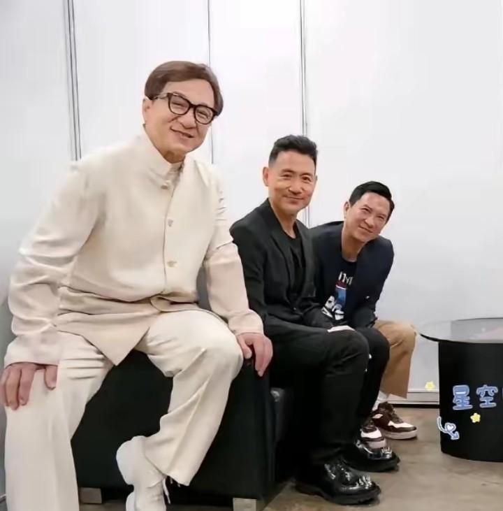 左边的是成龙，坐在中间的是张学友，两位都是能演会唱的大明星，而右边这位是谁？笑容