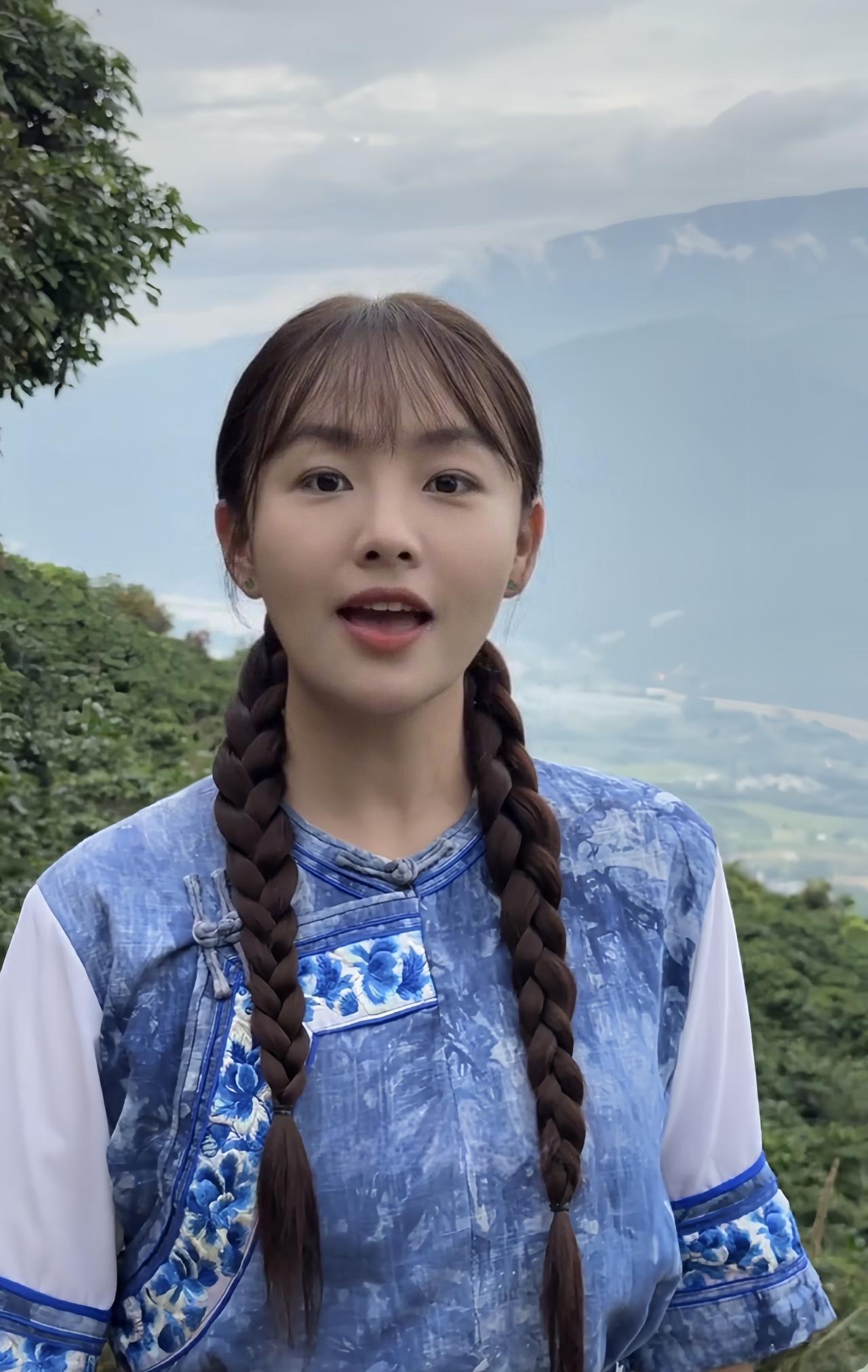 《唱的幸福落满坡》
山巅阿妹辫子拖，蓝衫绣彩映青坡。
开腔唱得云儿醉，幸福随歌满