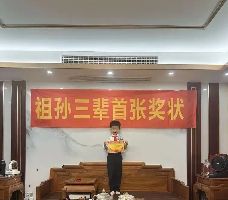 “祖孙三辈首张奖状”火了。小男孩骄傲地拿出奖状，站在家里的沙发上留影纪念，背后的