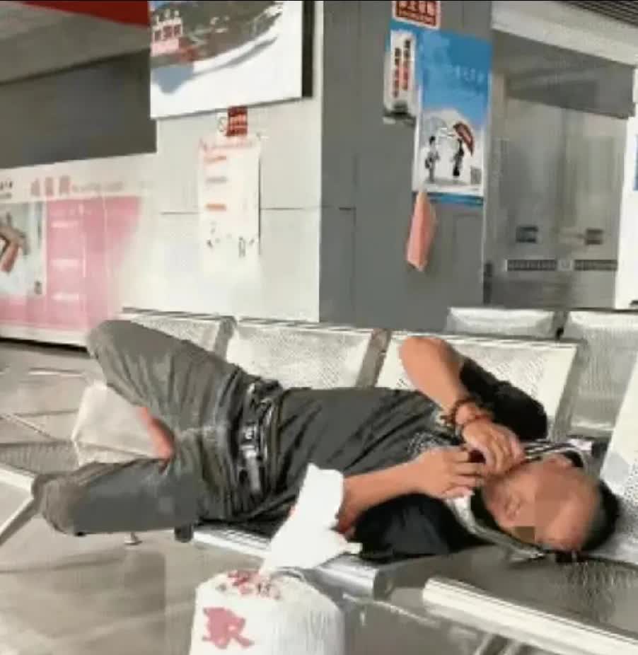 一男子在等火车，发现还有等两个小时才检票，他就躺在铁椅子上睡一会！
椅子不够长