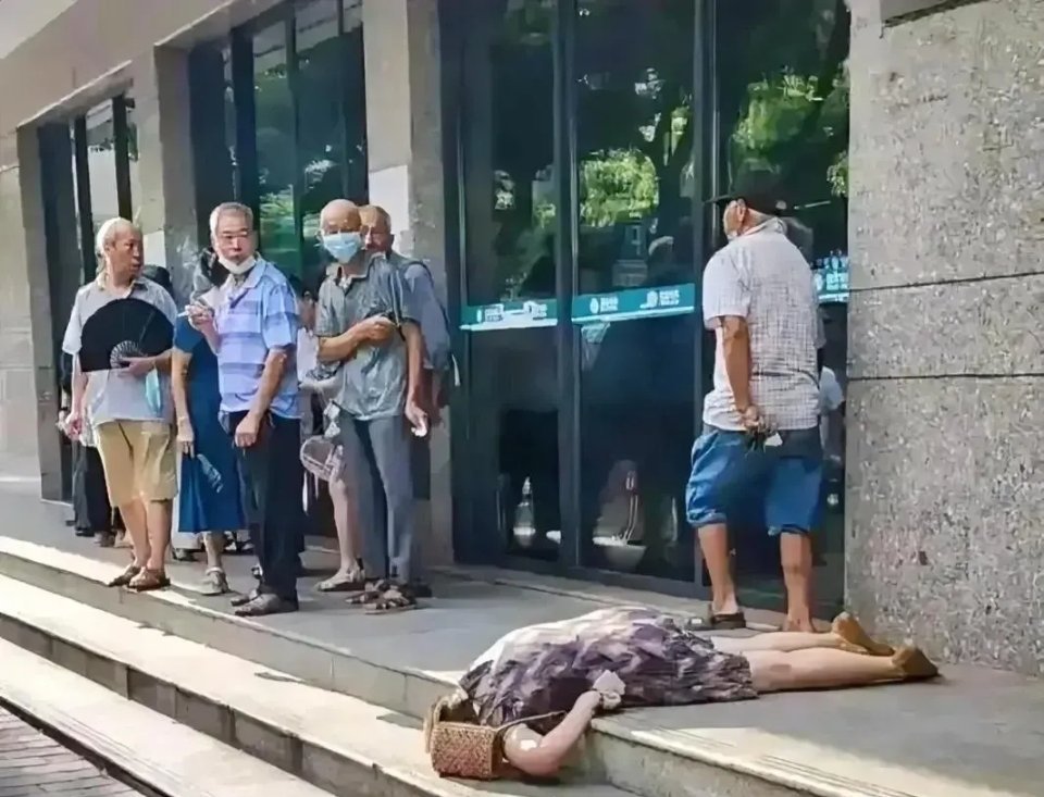 一家银行门口，一名中年女子突然倒地，群众围观着，就是没有人敢动。
这个女子一直趴