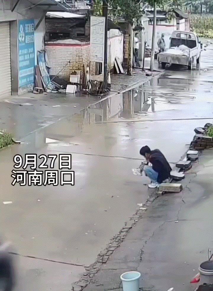 太危险了！奶奶带着孙子蹲在门口马路边上玩，期间一辆黑色轿车突然快速从奶孙俩身边驶