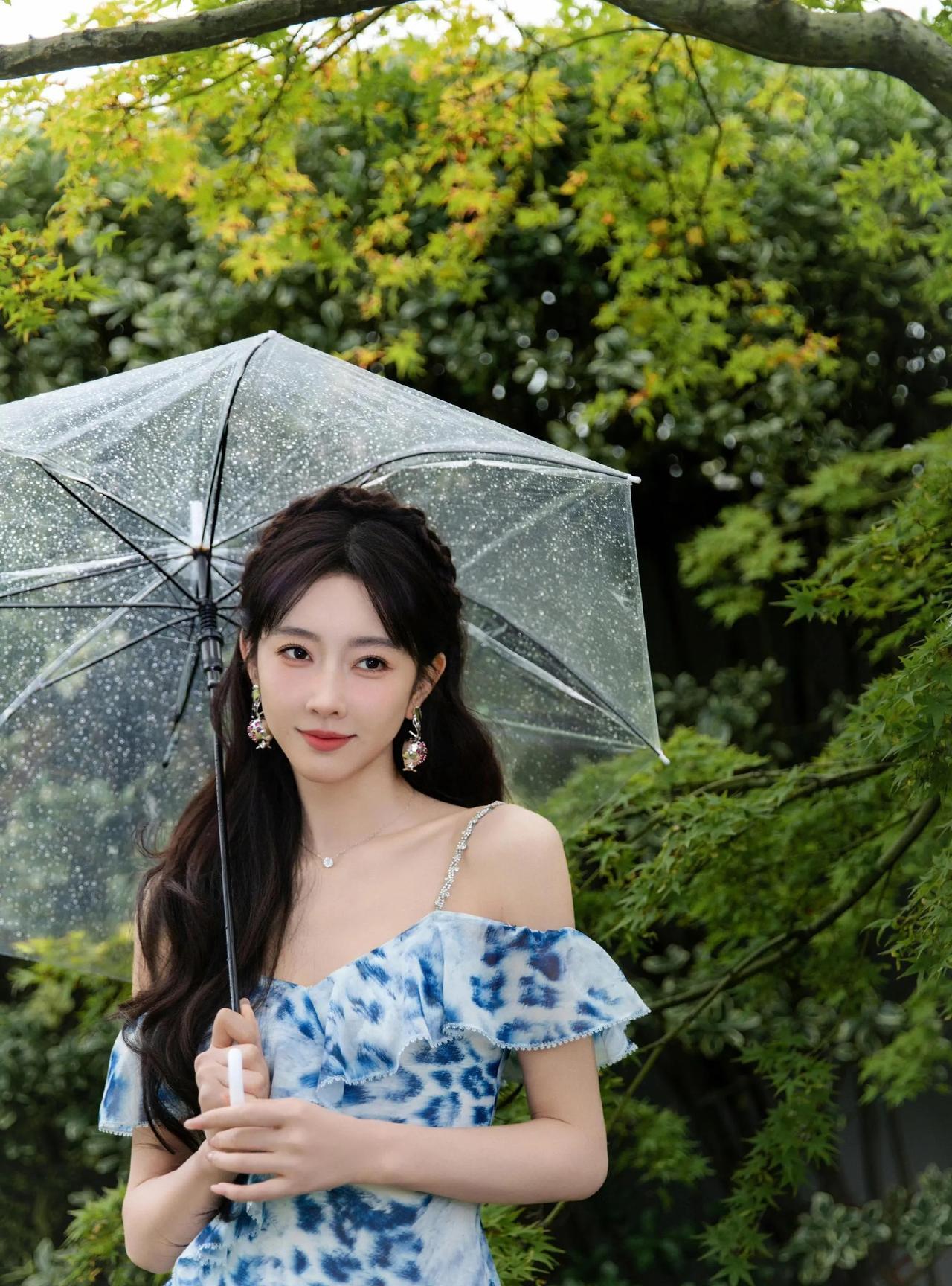 撑透明伞的宣璐，浅蓝印花裙轻扬发丝，雨日清新迷人