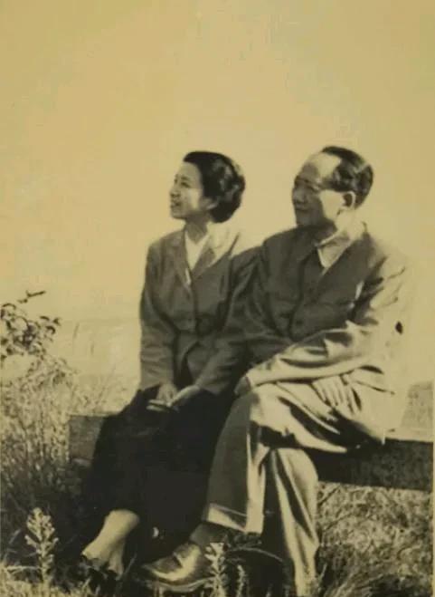 上世纪五十年代，在庐山，两个人坐在石凳上。周围是草地，当时天气不错，风轻云淡。他
