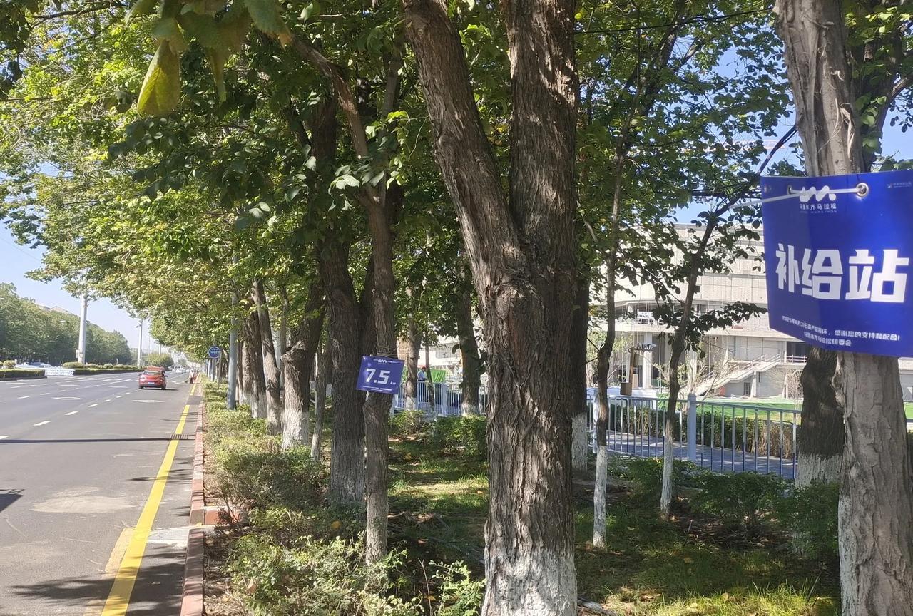 我看到了喀什东路的2025乌鲁木齐马拉松比赛的一个“补给站”和“7.5公里”路标
