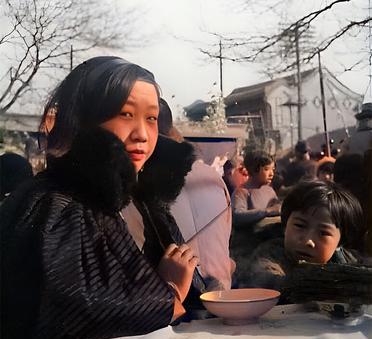 这是三十年代在北京一处庙会上的食摊上一位阔太太带着孩子将要吃饭。阔太太长着一张大